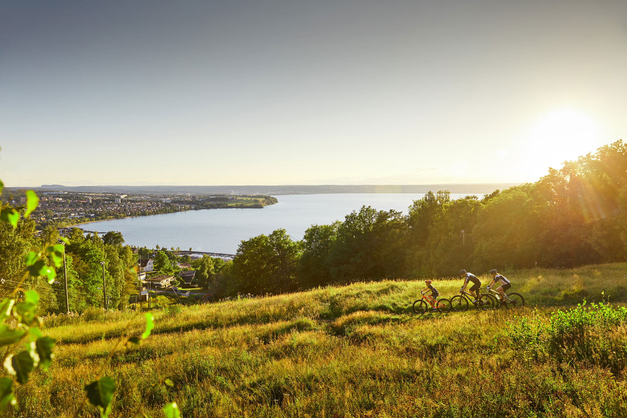 Mountainbike-cyklister i kvällssol med Vättern i bakgrunden