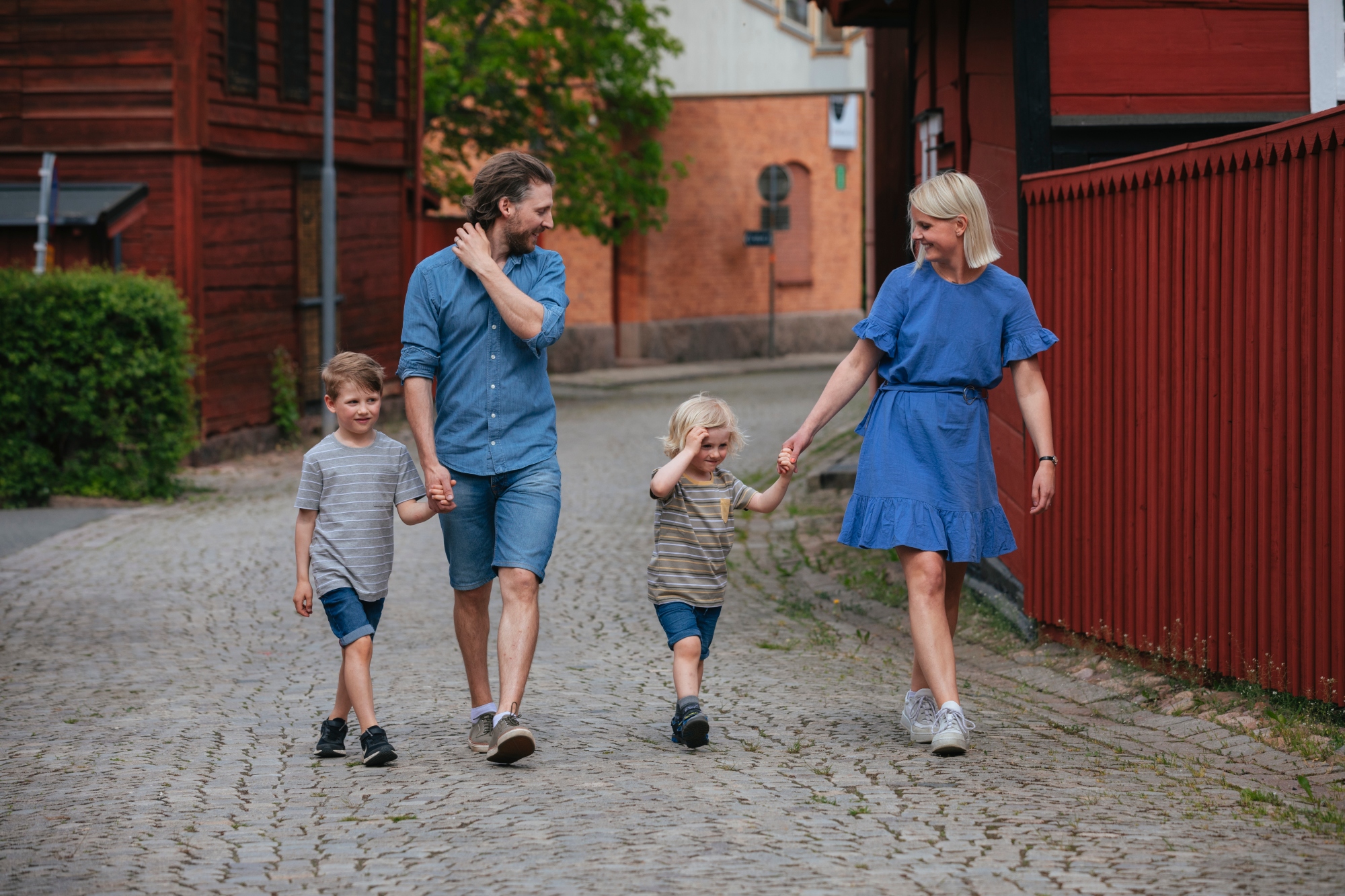 En familj med två barn som är ute och går längs med röda hus i Eksjö.