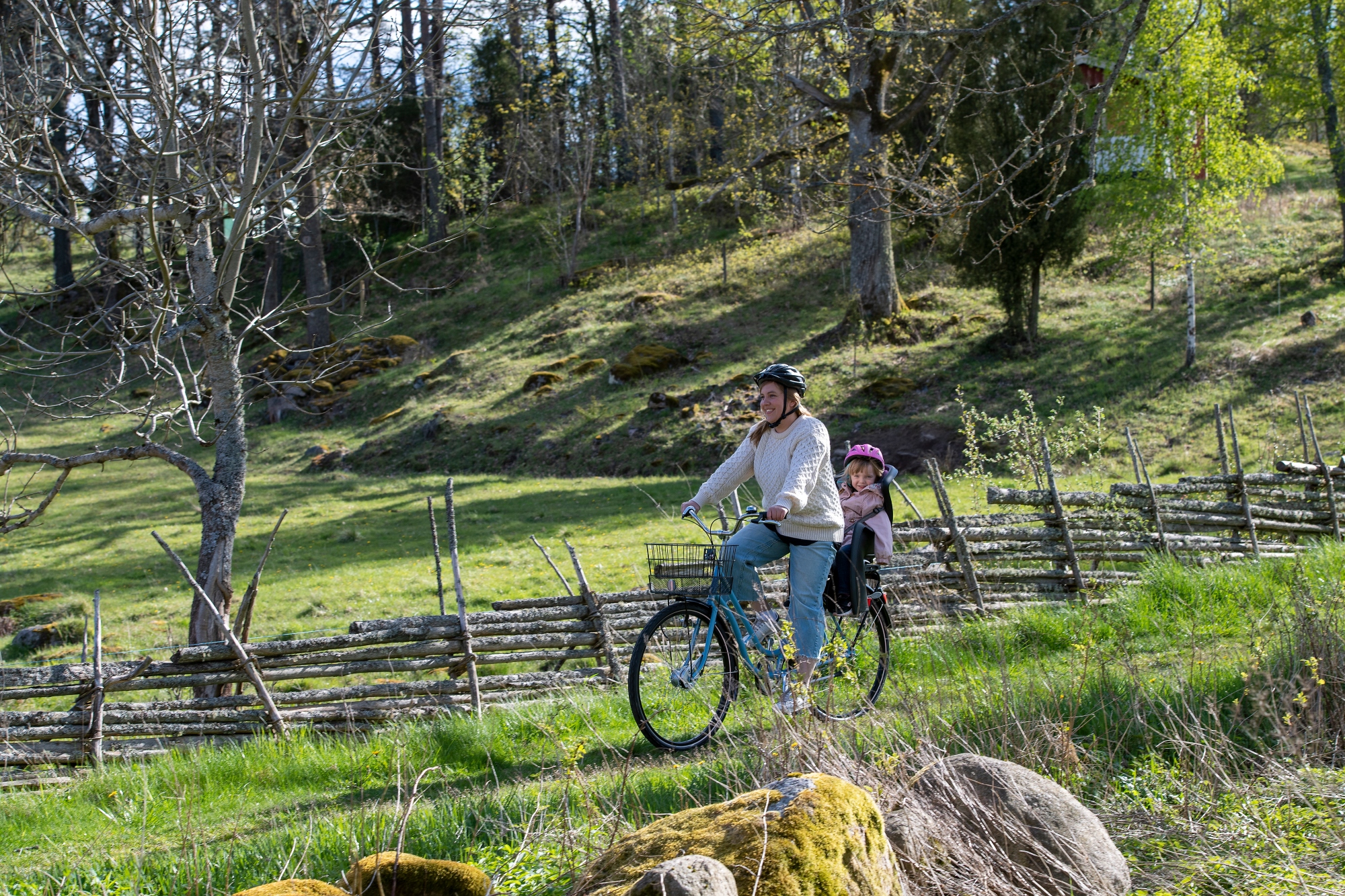 Kvinna och barn som cyklar längs med en vårig skogsväg