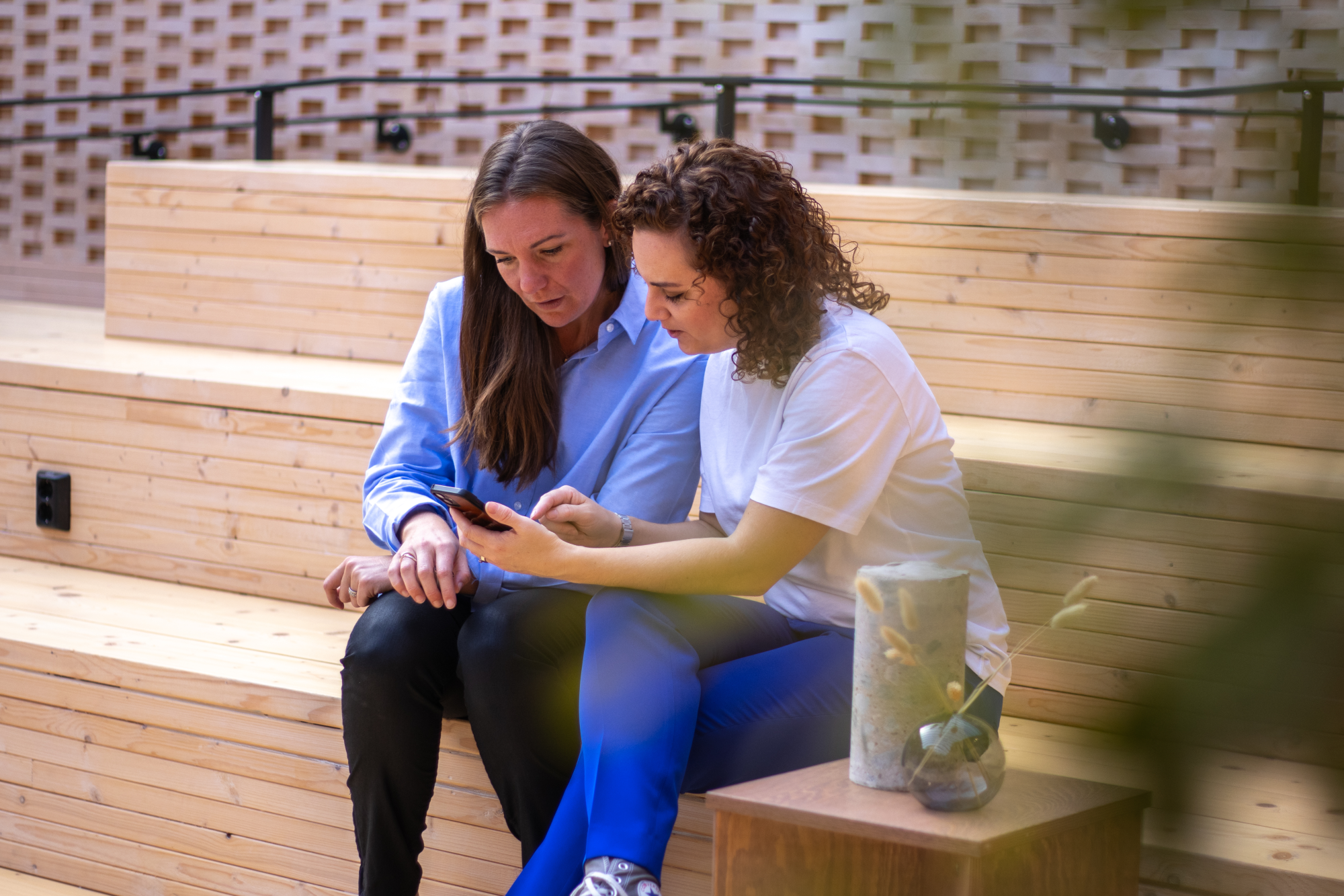 Två personer som tittar på något som ena personen håller fram på mobilen