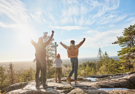 Människor som blickar ut mot horisonten ståendes på ett berg med händerna upp i luften av glädje.